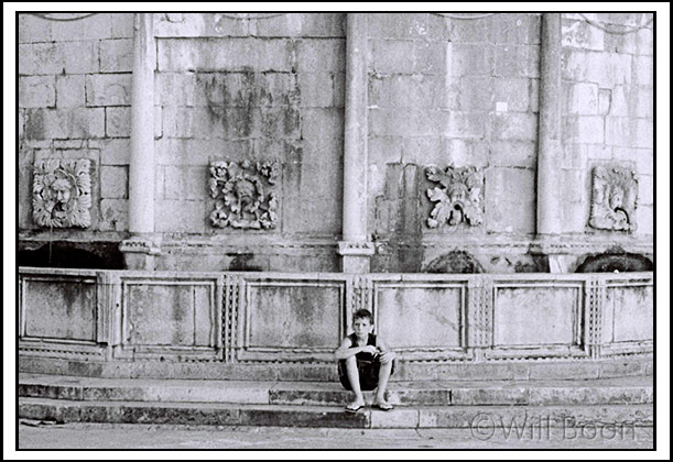 Young boy resting beside a water fountain, Dubrovnik, Croatia