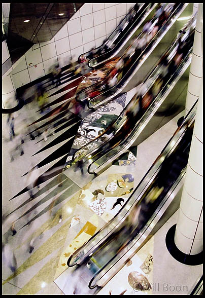 Commuters
 descending escalators, Dhoby Ghaut MRT subway station, Singapore